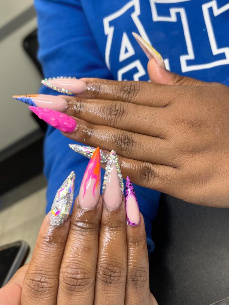 Long stiletto nails with a variety of designs and added rhinestones.